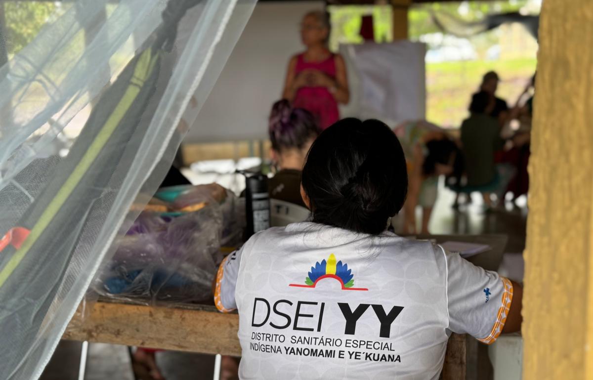 Foto mostra mulher de costas assistindo a palestra com camiseta da DSEI YY
