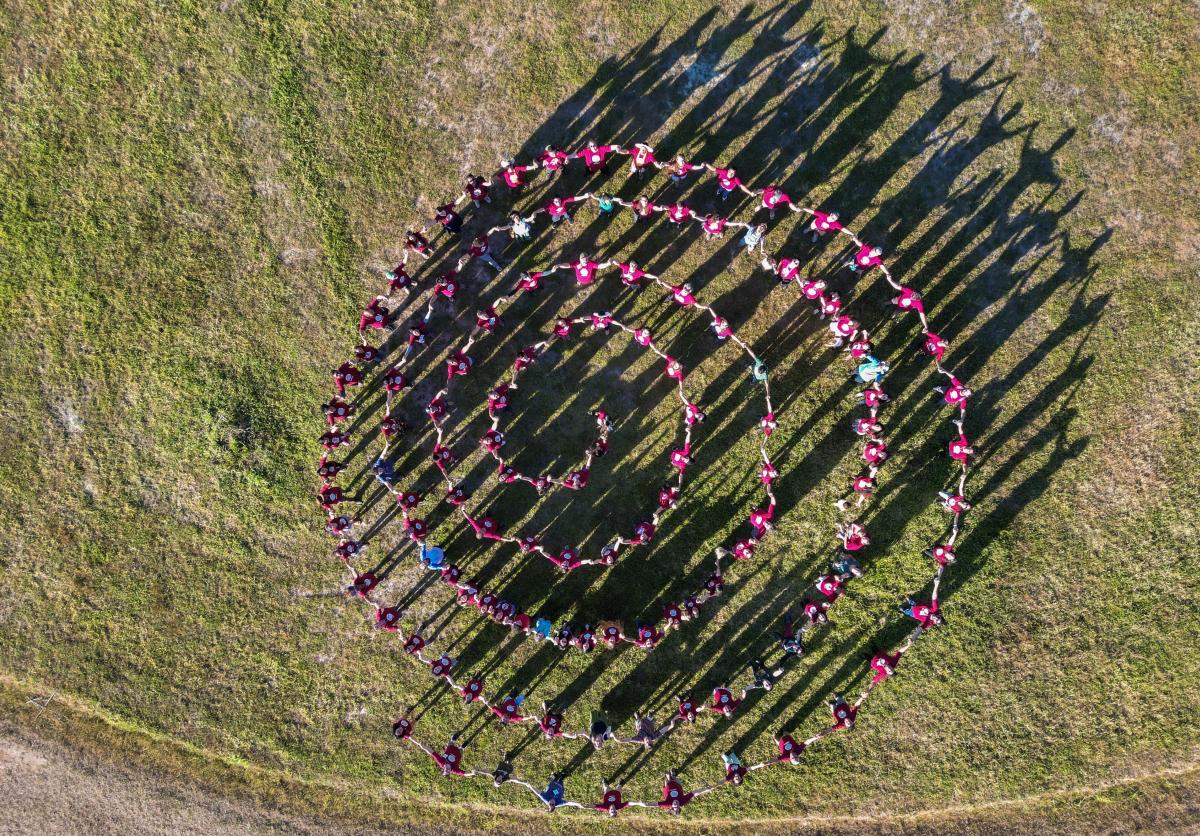 Foto aérea dos participantes do Encontro do Redário em 2023. Visto de cima, eles formam uma espiral