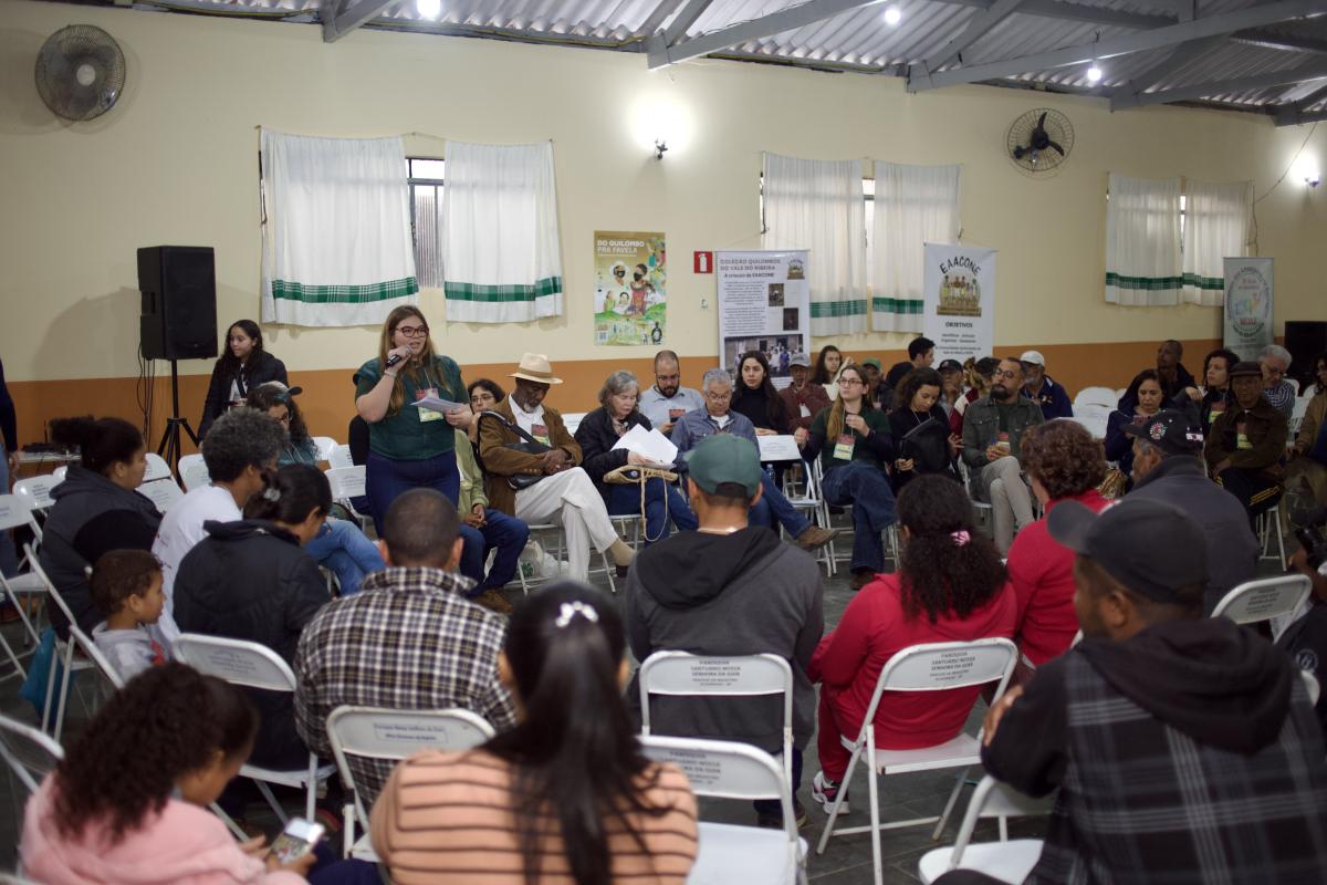 Foto mostra roda de conversa com muitas pessoas. Elas discutem a questão das sementes