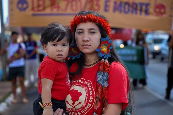 Sâmela Sateré Mawé com seu filho, Wynoã. Ela apresenta o quadro "Mães em Movimento", que traz à tona os desafios da maternidade para mulheres ativistas, que equilibram a luta pelos direitos dos povos com o cuidado cotidiano, ancestral e político de seus filhos